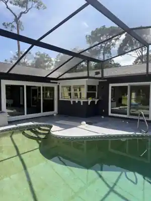 Screened pool enclosure over a swimming pool with sliding glass doors and large surrounding glass panels, from a Shore Tint & More window-film job