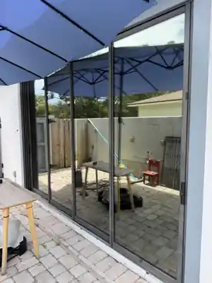 Large sliding patio glass doors from a Shore Tint & More job, reflecting a patio umbrella and sky in daylight